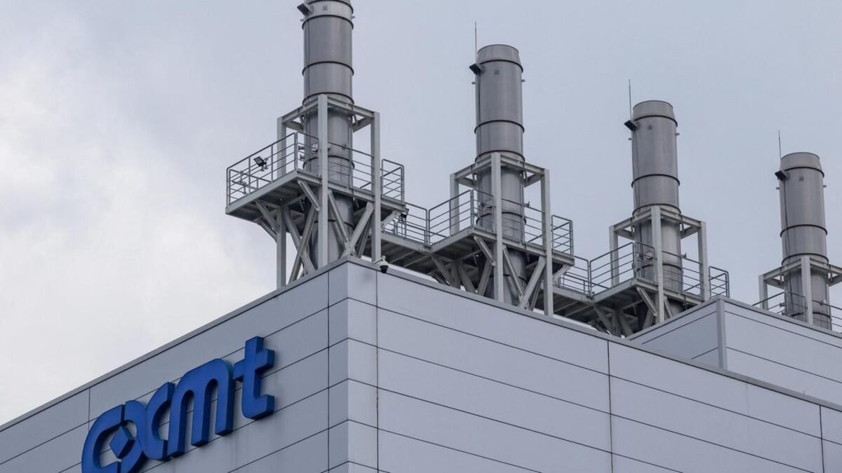 The roofline of a CXMT fabrication plant, with the blue cxmt logo mounted on grey cladding below four tall exhaust stacks