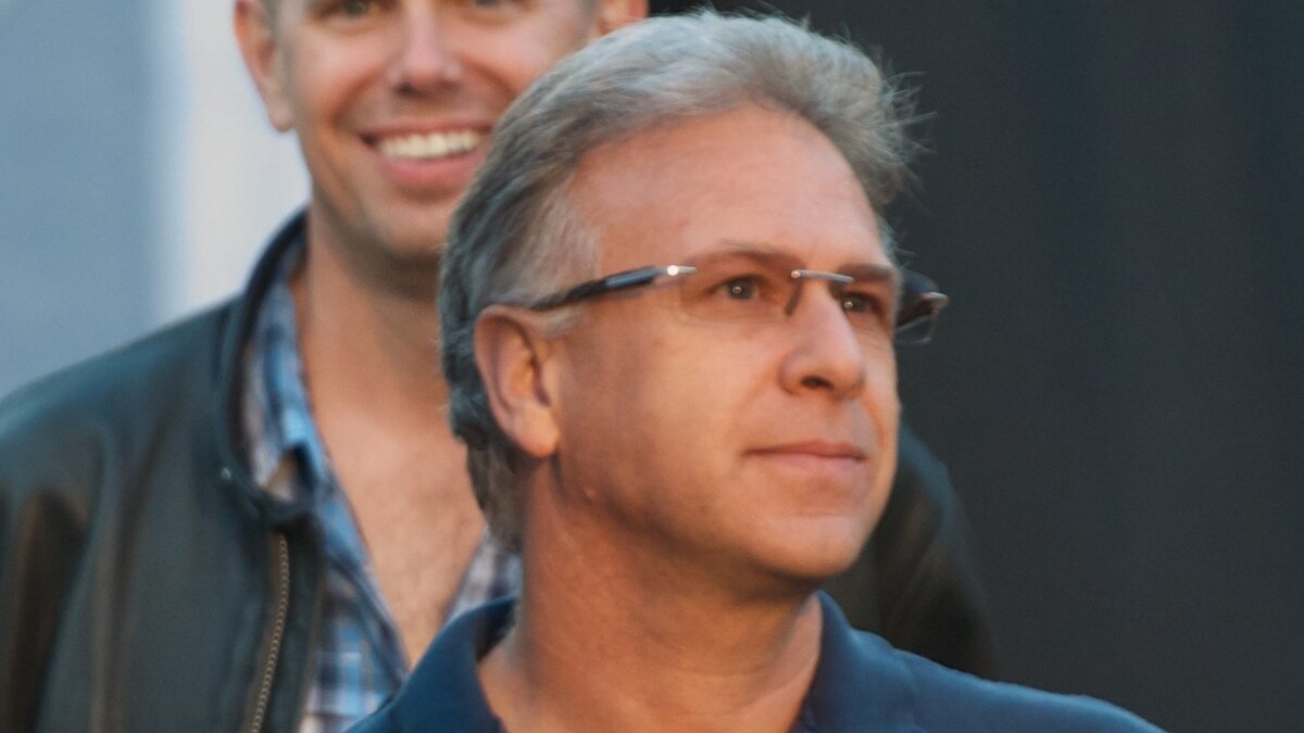 Phil Schiller in rimless glasses and a navy polo shirt, standing in a crowd at Apple's 2012 developer conference
