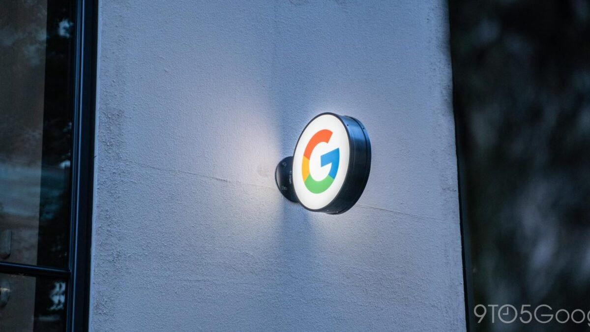 An illuminated multicolored Google G logo mounted on the wall of a Google building at dusk.
