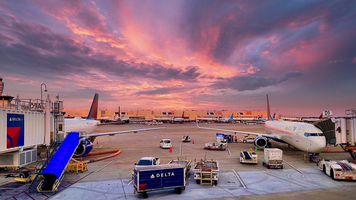 Delta aircraft parked at jet bridges on the apron at Hartsfield-Jackson Atlanta International Airport under a pink sunset sky
