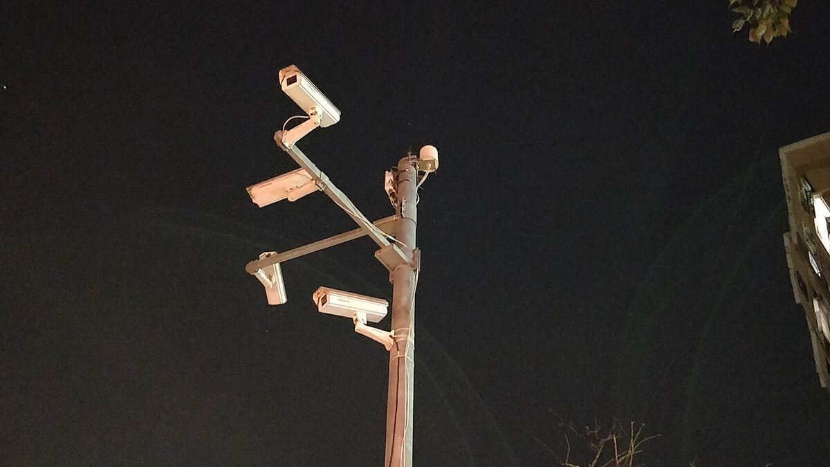 A cluster of surveillance cameras mounted on a pole at night.