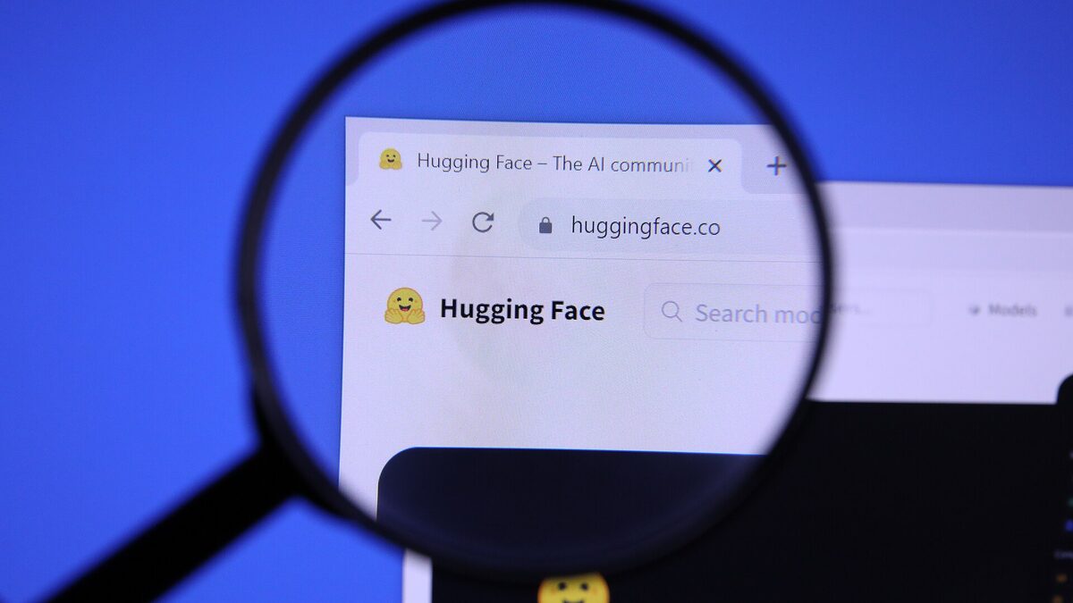 The Hugging Face homepage and its yellow emoji logo viewed through a magnifying glass