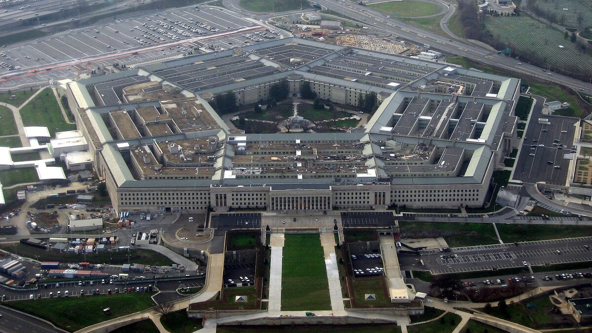 Aerial photograph of the Pentagon's five concentric rings and central courtyard, ringed by parking lots and highway interchanges on a bare winter day.