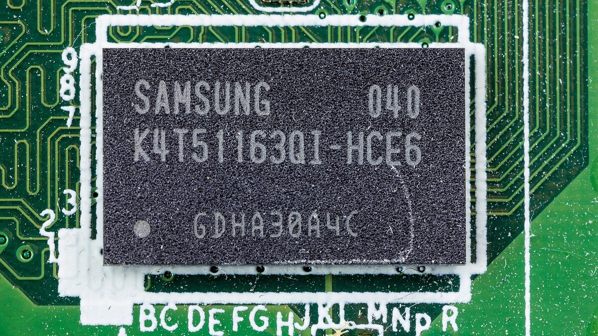 Macro photograph of a Samsung-branded DRAM chip soldered to a green circuit board, its part number K4T51163QI-HCE6 clearly legible