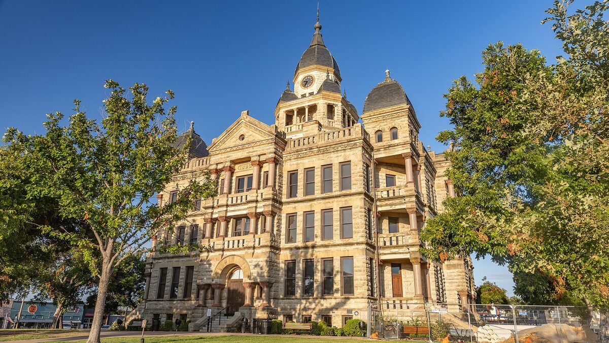 A stone courthouse with a clock tower against a blue sky, standing in for the U.S. and U.K. courts now prosecuting Scattered Spider members.