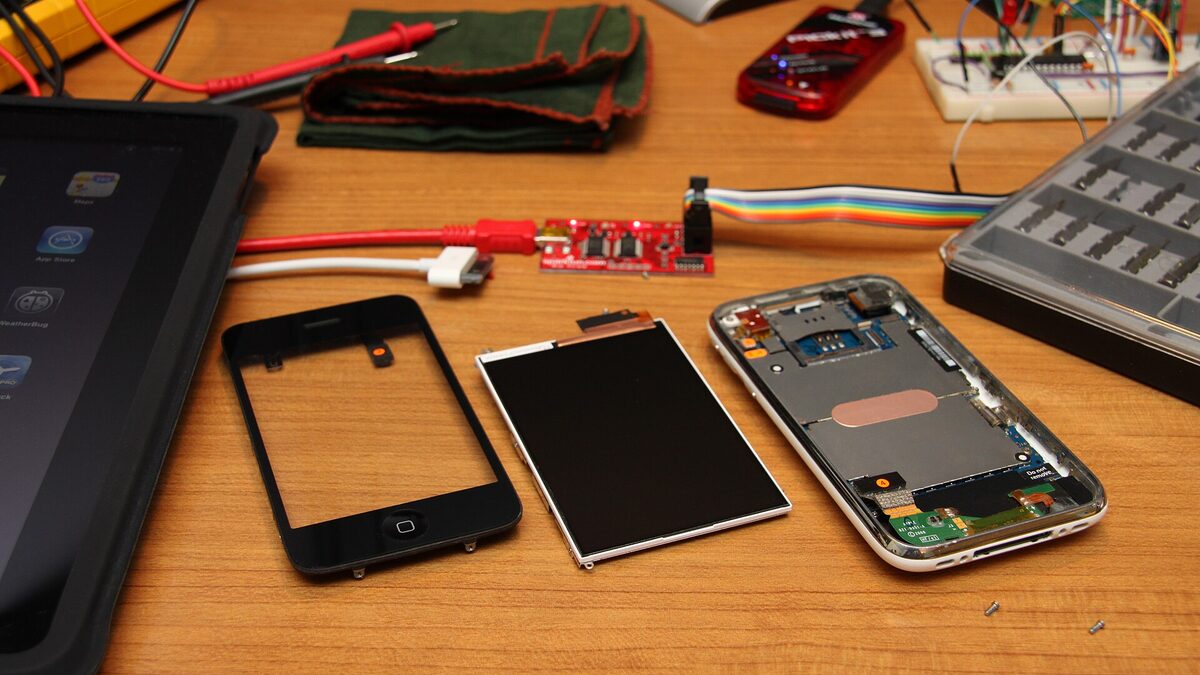 An iPhone disassembled into its logic board, battery, and camera components, the kind of manufacturing detail the Tata Electronics leak exposed.