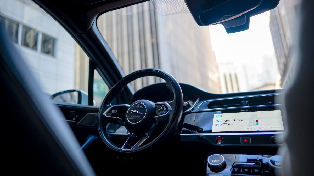 Interior of a Waymo robotaxi showing the empty driver's seat and steering wheel.