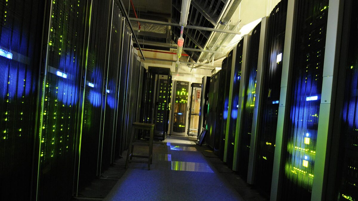 A dark server room lined with racks of blinking network and compute hardware